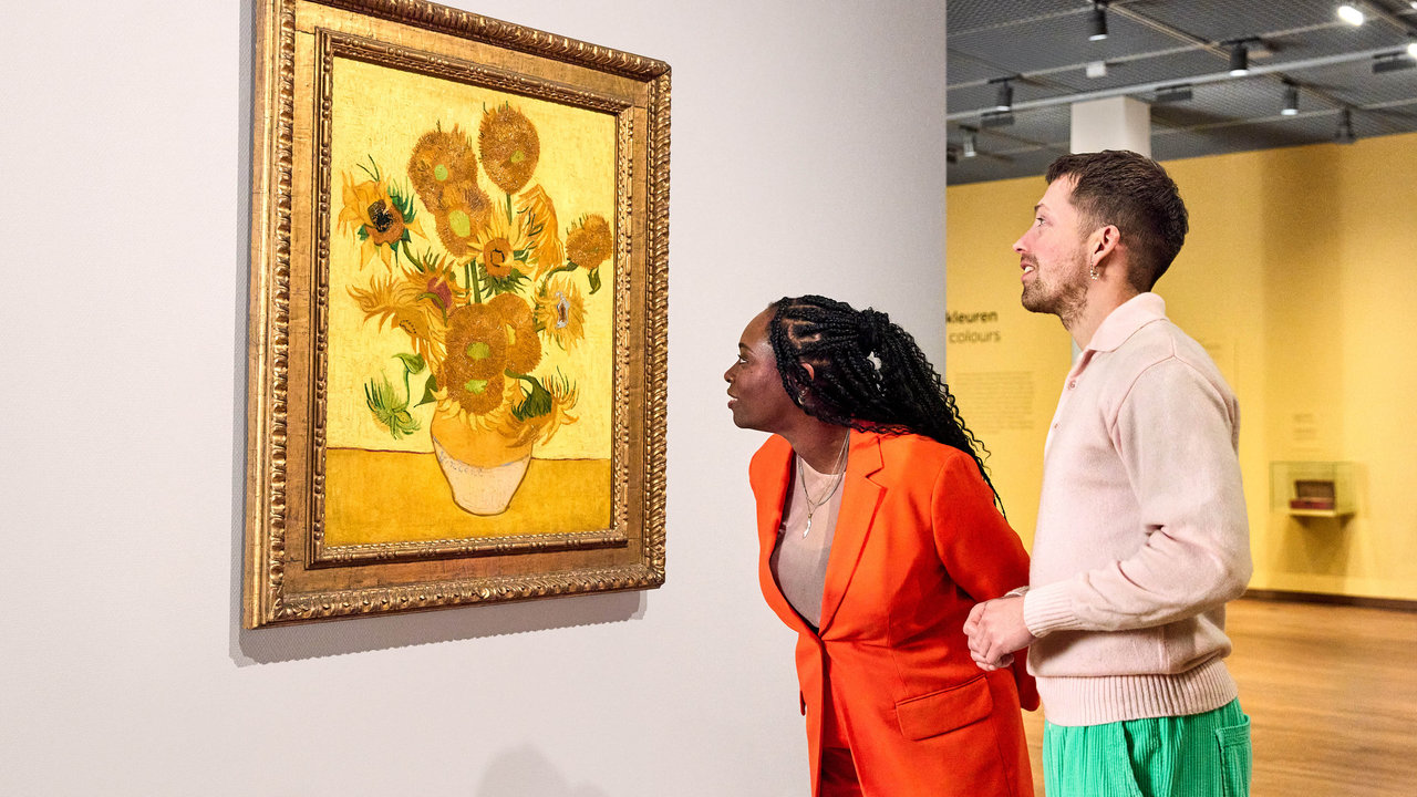 Een bevriend stel kijkt naar het schilderij Zonnebloemen van Vincent van Gogh in het Van Gogh Museum. De vrouw helt wat voorover om het werk nog beter te zien. Foto Suzanne Karsters