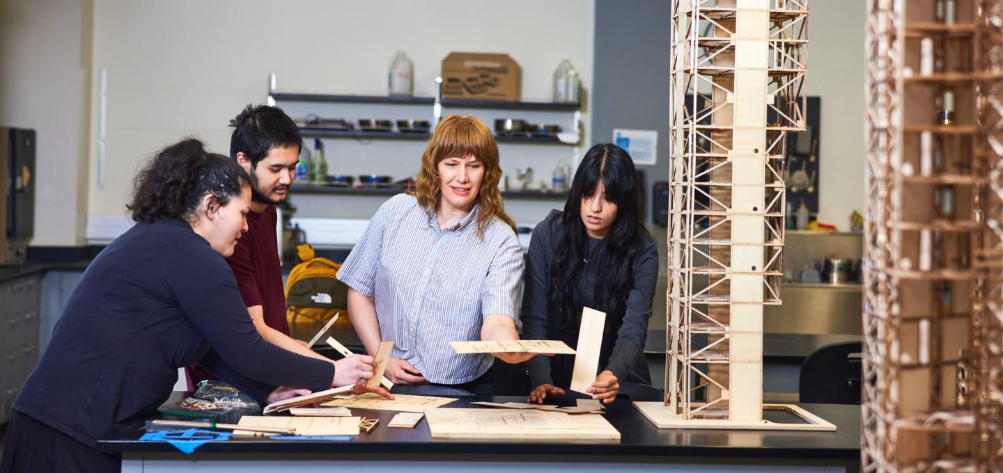Close-up of PSU students carefully assembling a laser-cut wooden structural model